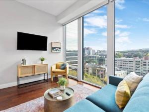 a living room with a blue couch and a large window at CozySuites Dream 1BR, PPG Paints Arena, Pitts in Pittsburgh