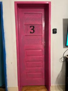 una porta rosa con il numero tre sopra. di Rostelbem Guesthouse Lisbon a Lisbona