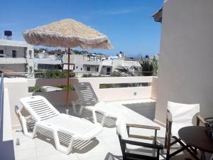 a group of chairs and an umbrella on a balcony at Maria Apartments in Agia Pelagia