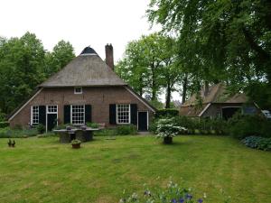 an old brick house with a thatched roof at Landgoedhoeve Vosbergen in Heerde