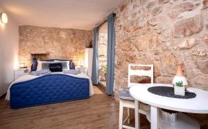 een slaapkamer met een blauw bed en een stenen muur bij Unique Stone House Apartment -Free parking in Stari Grad