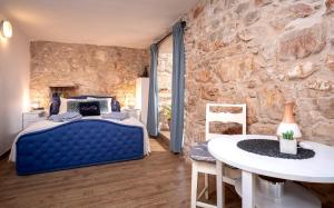 a bedroom with a blue bed and a stone wall at Heritage Stone House Retreat -Free parking in Stari Grad