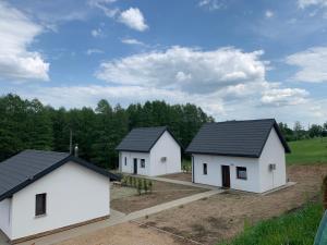 un grupo de tres edificios blancos en un campo en Przystań nad Legą en Olecko