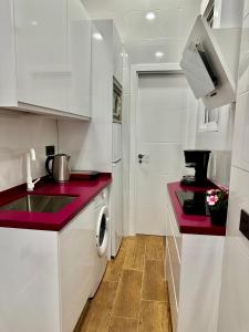 a kitchen with white cabinets and red counter tops at Love Pink Gran Via in Madrid