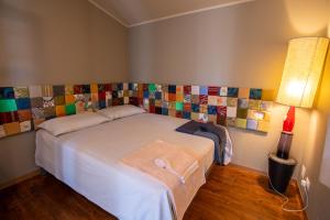 a bedroom with a white bed with a colorful wall at Cottage sul lago - Officina Didattica in Donnalucata