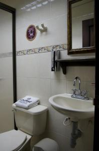 a bathroom with a sink and a toilet and a mirror at Hospedaje Casa Real in Salamina