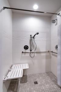 a white bathroom with a bench and a shower at Residence Inn by Marriott La Quinta in La Quinta