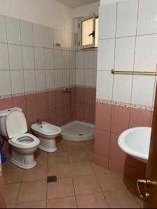 uma casa de banho com 2 WC, uma banheira e um lavatório. em Martin Apartment em Vlorë