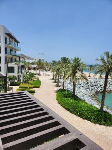 vistas a una playa con palmeras y a un edificio en The Address Residences Fujairah en Fujairah