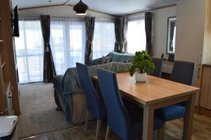 a dining room and living room with a wooden table and blue chairs at River View Retreat in Offenham