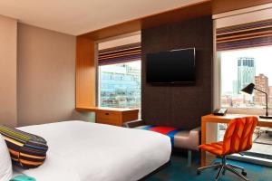 a hotel room with a bed and a desk and a television at Aloft Chicago Downtown River North in Chicago