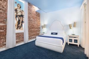 a bedroom with a white bed and a brick wall at The Saint Hotel, New Orleans, French Quarter, Autograph Collection in New Orleans