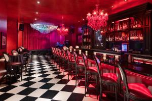 a bar with red walls and black and white checkered floor at The Saint Hotel, New Orleans, French Quarter, Autograph Collection in New Orleans