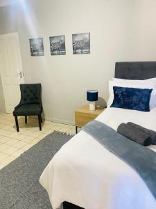 a bedroom with a large bed and a chair at The Home in Richards Bay