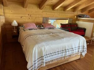 ヴェゾナにあるChalet Lombardieのベッドルーム(大型ベッド1台、赤いソファ付)