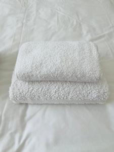 a white towel laying on top of a bed at Seaside Rooms Gorleston in Gorleston-on-Sea