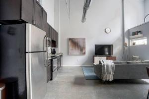 a kitchen with a refrigerator and a living room with a couch at CozySuites l 2BR Loft, Monument Circle, Indy in Indianapolis
