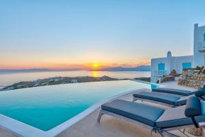 una piscina con sedie e un tramonto sullo sfondo di Mermaid Luxury Villas - Aquata Private pool a Fanari