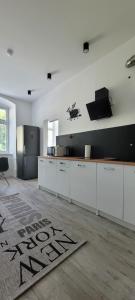 a kitchen with white cabinets and a rug on the floor at Apartament CityStation in Wałbrzych