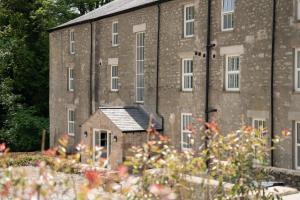 an old brick building with a garden in front of it at Bronte Apartment - Dales - Lakes - Kirkby Lonsdale in Carnforth