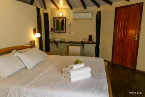 - une chambre avec un lit et des serviettes dans l'établissement Pousada Villa Luna, à Penedo