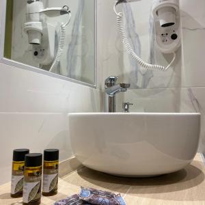 ein Badezimmer mit einem weißen Waschbecken und einem Spiegel in der Unterkunft Pansion Argo in Nea Moudania