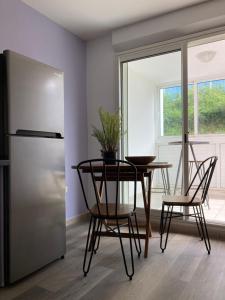 una cucina con tavolo, sedie e frigorifero di Ananas appart a Saint-Denis