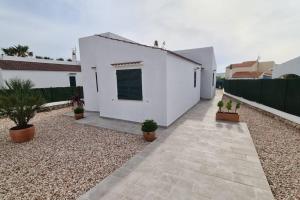 ein weißes Haus mit Topfpflanzen im Innenhof in der Unterkunft Villa Mar. En Ciudadela Menorca in Cala'n Bosch