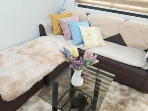 a couch with pillows and a vase of flowers on a table at Family Group Affordable Staycation in tagaytay in Tagaytay