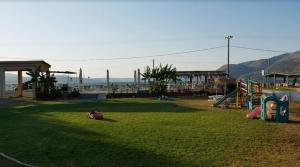 Camping Argostoli في أرغوستولي: حديقة بها ملعب ومعدات لعب