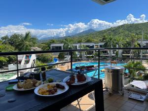 una mesa con platos de comida en un balcón con piscina en Hermoso apartasol en santafe de Antioquia., en Santa Fe de Antioquia