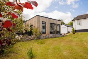 a wooden house with glass windows in a yard at Ardvreck Chalet self-catering in Kyleakin