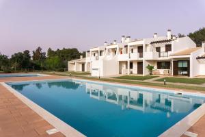 uma grande piscina em frente a uma casa em RochAlvor em Alvor