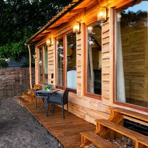 a wooden cabin with a table on the porch at La vie en Rose - Pet friendly Tiny house in the nature with fenced garden in Torhout