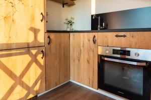 a kitchen with wooden cabinets and a black oven at La vie en Rose - Pet friendly Tiny house in the nature with fenced garden in Torhout