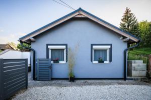 una casa blu con due finestre e una recinzione di Orchidea Apartman a Balatonkenese
