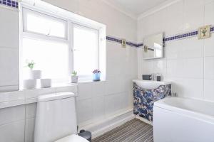 a white bathroom with a toilet and a window at Elegant 3 Bedroom House in Basildon - Essex Free Parking & Superfast Wifi, upto 6 Guests in Basildon