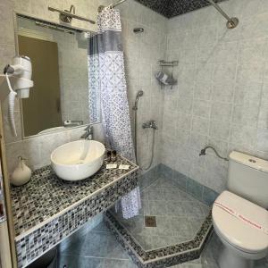 ein Bad mit einem Waschbecken, einer Dusche und einem WC in der Unterkunft Pansion Argo in Nea Moudania