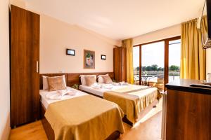 a hotel room with two beds and a balcony at Hotel CASA ROYAL pe plaja Belona in Eforie Nord