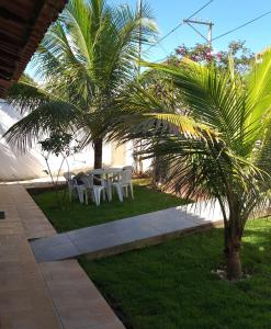 un patio con una mesa, sillas y una palmera en Hostel Suite Home en Saquarema