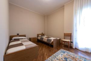 um quarto com 2 camas, uma cadeira e uma janela em Nonna Elvira Holiday House em Bondone