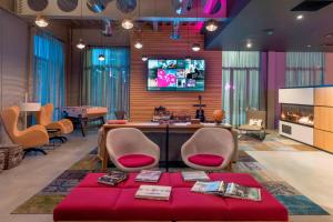 a lobby with a table and chairs and a tv at Moxy London Excel in London