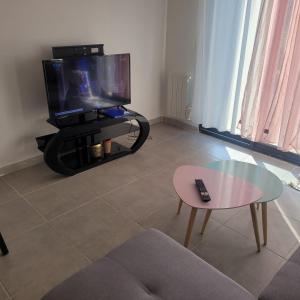 a living room with a tv and a glass table at Joli nid douillet in Les Sorinières