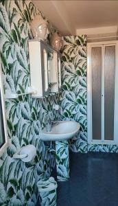 a bathroom with a sink and a leafy wallpaper at Casa vacanze Isolotto in Isola delle Femmine