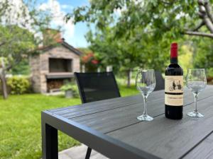 - une bouteille de vin assise sur une table en bois avec 2 verres à vin dans l'établissement Apartment River, à Klis