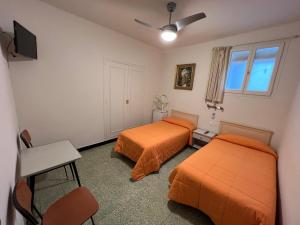 2 letti in una camera con lenzuola arancioni di Hostal Zurich a Sant Feliu de Guíxols