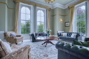 a living room with blue furniture and large windows at Rumwell Park - 8 Bedroom Manor House- Taunton in Taunton