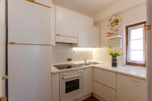 - une cuisine blanche avec des placards blancs et un évier dans l'établissement Appartamento centralissimo con wi-fi, à Cortina dʼAmpezzo