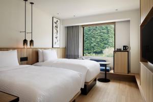 two beds in a hotel room with a window at Fairfield by Marriott Tochigi Motegi in Motegi