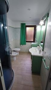 un bagno con due lavandini e un water e mobili verdi di Casa vacanze Tortolì a Tortolì Altre 5 foto
